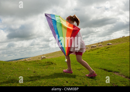 Un dai capelli rossi ragazza con un arcobaleno kite on Maiden Castle, Dorchester Dorset, Foto Stock