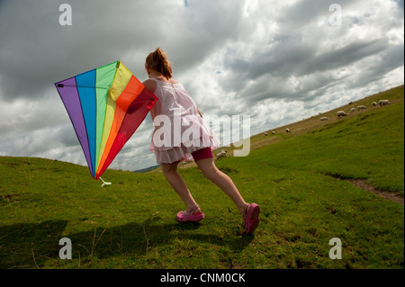 Un dai capelli rossi ragazza con un arcobaleno kite on Maiden Castle, Dorchester Dorset, Foto Stock