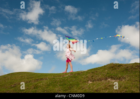 Un dai capelli rossi ragazza con un arcobaleno kite on Maiden Castle, Dorchester Dorset, Foto Stock