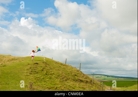 Un dai capelli rossi ragazza con un arcobaleno kite on Maiden Castle, Dorchester Dorset, Foto Stock