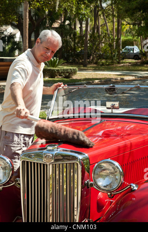 Uomo maturo prepara la sua annata 1953 mg convertibile per una gita. Foto Stock