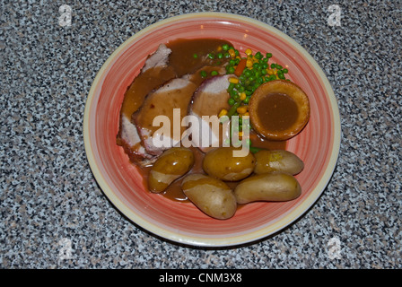 Lombo di maiale patate di primizia fa pipì granturco dolce e Yorkshire pudding arrosto sulla piastra con fatti in casa con sugo di carne Foto Stock