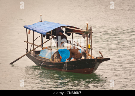 Due pescatori pesca in una piccola barca di Halong Bay, Quang Ninh, Vietnam Foto Stock