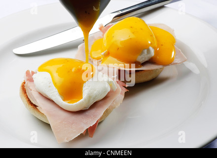 Piatto di uova Benedict due metà di muffin inglese e rabboccato con prosciutto o pancetta uova in camicia e salsa olandese colazione brunch Foto Stock