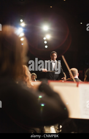 Il conduttore sventolando baton oltre orchestra Foto Stock