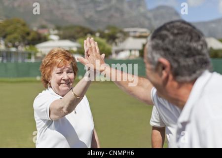 Anziana coppia alta fiving all'aperto Foto Stock