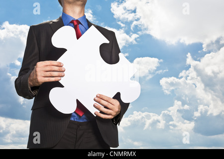 Imprenditore tenendo pezzo di puzzle Foto Stock