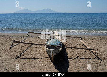 Tradizionale Fisherman's outrigger sulla spiaggia a Dili Timor Leste, con isola di Atauro all'orizzonte. Foto Stock