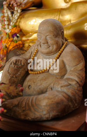 Buddha Sorridente pietra scolpita statua seduta al piede del buddha di oro, Wat Phra That Chae Haeng, Nan Foto Stock