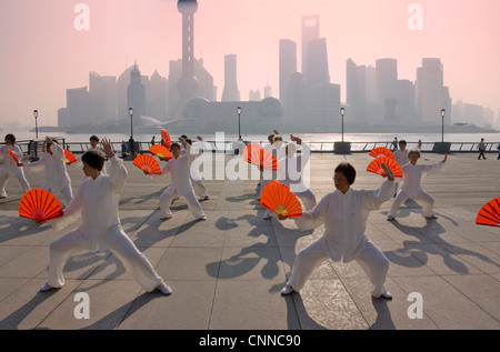 Persone che praticano il Taiji con ventole rosso sul Bund, Pudong skyline di distanza, Shanghai, Cina Foto Stock