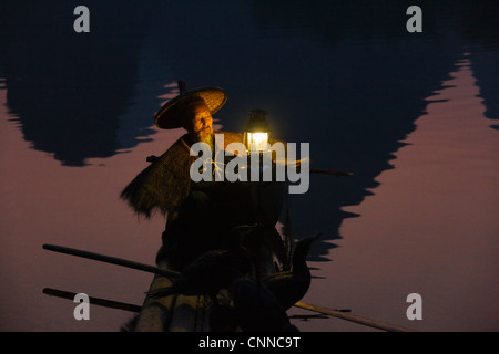 Pescatore lanterna di illuminazione su zattera di bambù al crepuscolo, Yangshuo, Guangxi, Cina Foto Stock