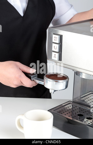 Foto di un barista mettendo un porta-filtro pieno di caffè appena macinato in una macchina per caffè espresso. Foto Stock