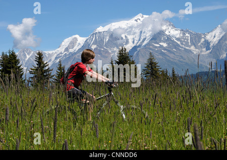 Ragazzo in sella in bicicletta in montagna, alpi, Francia Foto Stock