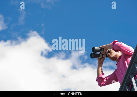 Uomo che guarda attraverso il binocolo Foto Stock