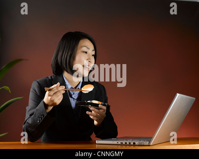 Imprenditrice di mangiare e di lavorare alla scrivania Foto Stock