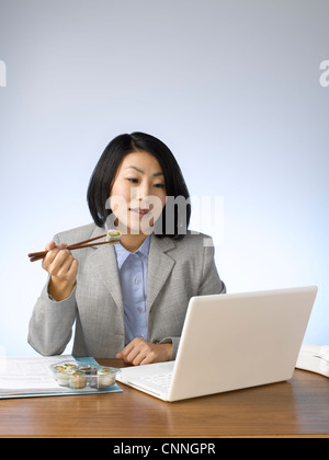 Imprenditrice di mangiare e di lavorare alla scrivania Foto Stock
