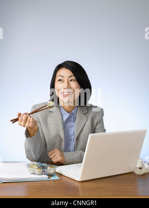 Imprenditrice di mangiare e di lavorare alla scrivania Foto Stock