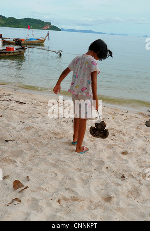 Bambina mettendo il granchio a ferro di cavallo torna nel mare,parte di un programma di conservazione per salvare il pesce,koh sukon,trang,thailandia Foto Stock