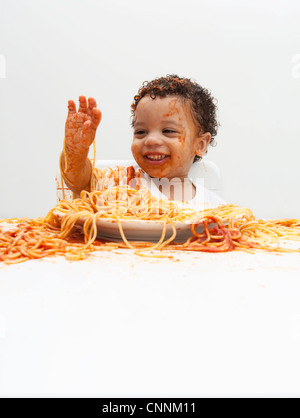 Ragazzo di mangiare gli spaghetti con le mani Foto Stock