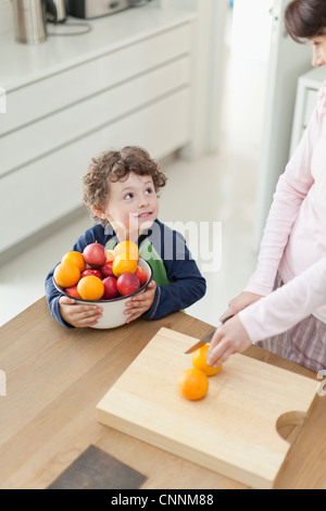 Madre e figlio per affettare frutta in cucina Foto Stock