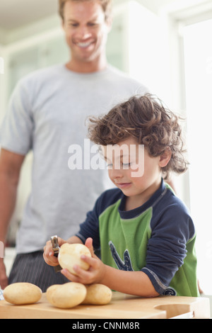 Ragazzo sbucciare le patate in cucina Foto Stock