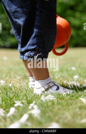 Gambe e piedi di bambina in piedi su erba in giardino, Farnham, Inghilterra Foto Stock