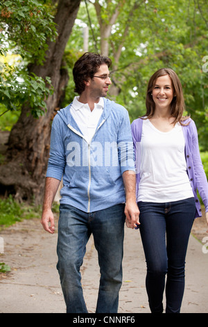 Coppia giovane a piedi attraverso il parco Foto Stock