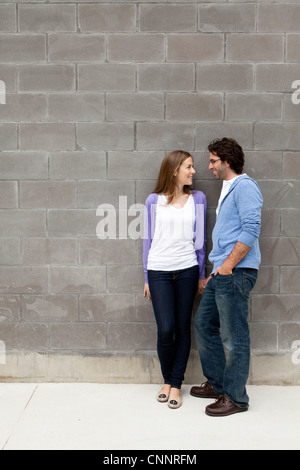 Coppia giovane in piedi di fronte a muro di pietra Foto Stock