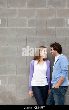 Coppia giovane in piedi di fronte a muro di pietra Foto Stock