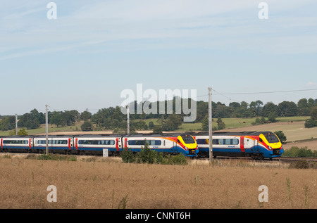 Due East Midlands classe treni 222 meridian treno accelerando attraverso la campagna inglese e in estate. Foto Stock