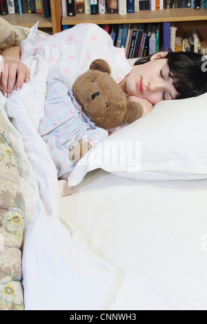 Donna abbracciando Teddy bear a letto Foto Stock