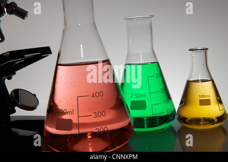 Microscopio da Ricerca e bottiglie da laboratorio con liquido colorato Foto Stock