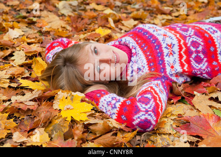 La donna posa in foglie di autunno Foto Stock