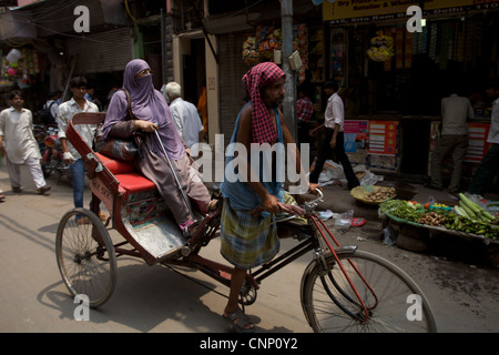 Una donna musulmana come ottenere un sollevamento su un rickshaw lungo la trafficata strada nella Vecchia Delhi, India Foto Stock