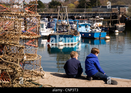 Lymington - Hants - la parete del porto - piccole ragazzi la pesca dei granchi - circondato da commerciale barche da pesca e ingranaggio Foto Stock
