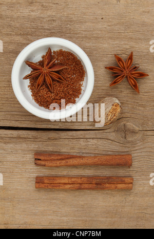 Il cinese cinque spezie in un ramekin con anice stellato la noce moscata e cannella sul vecchio legno stagionato Foto Stock