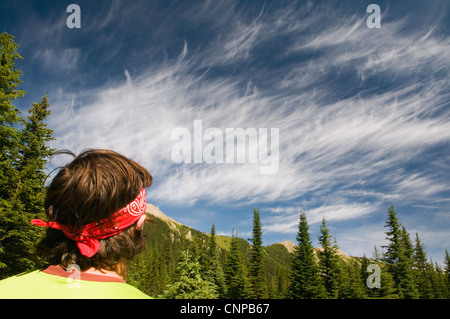 Giovane uomo guardando cirrus nuvole a Tumbling Creek sul sentiero di Rockwall, Kootenay Parco Nazionale del Canada, British Columb Foto Stock