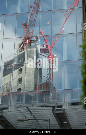 Un luogo, un nuovo edificio essendo costruito si vede riflessa nella parete di vetro dei vicini dell'edificio, il coccio. Foto Stock