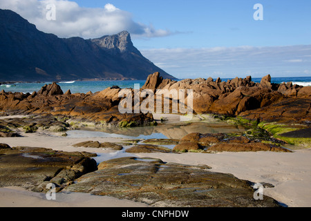 Kogel Bay Beach con rock in primo piano della montagna, a Kogel Bay, Sud Africa Foto Stock