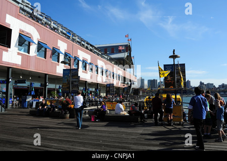 Blue sky view, verso East River, gente seduta a piedi pontile in legno sotto il nome di Bianco Pier 17, South Street Seaport, New York Foto Stock