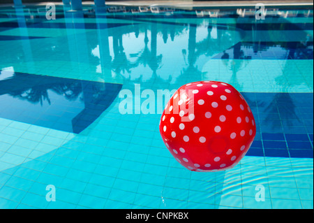 Red spotted palla spiaggia galleggiante nella piscina esterna Foto Stock