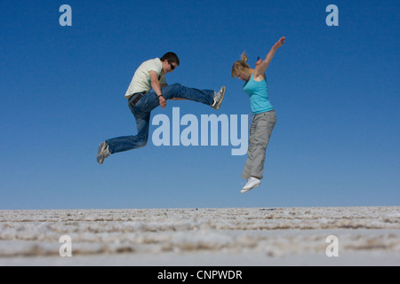 Un azione girato di una teenage fratello e sorella gioca combattimenti saltando in aria sulla grande vuoto salina in Bolivia Foto Stock