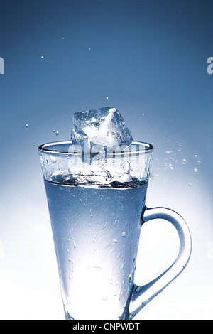 Il cubo di ghiaccio schizzi in un bicchiere di acqua, Foto Stock