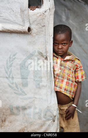 Un ragazzo sta alla porta di un rifugio temporaneo realizzato da UNHCR-fornito tarp al Miketo IDP insediamento, Katanga, NELLA REPUBBLICA DEMOCRATICA DEL CONGO Foto Stock