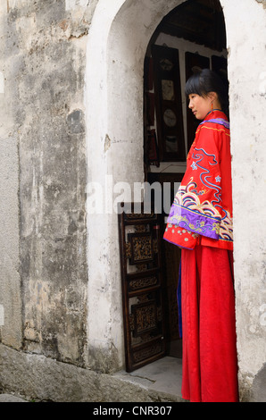 Profilo di una nuova sposa che indossa il suo red abito da sposa alla porta di un antico villaggio di hongcun edificio della provincia di Anhui cina Foto Stock