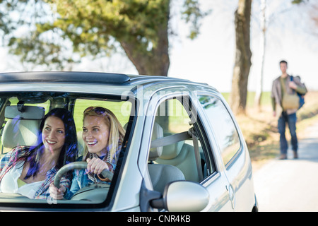 Due donne felice in macchina prendendo bello sollevatore-escursionista road trip Foto Stock