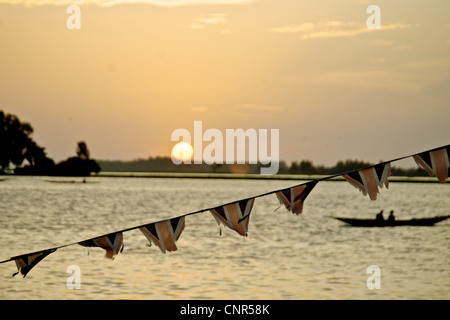 Strappate le bandiere e la silhouette di una piroga sul fiume in Mopti, Mali. Foto Stock