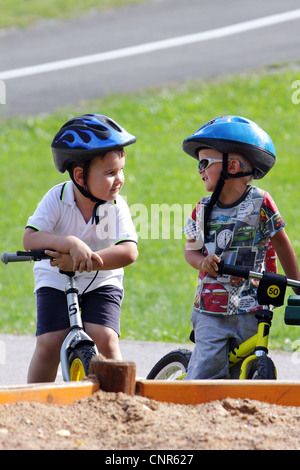 Discutendo di due baby boys sul traffico parco giochi per bambino con casco Foto Stock