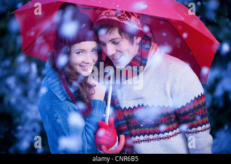 Coppia sorridente sotto ombrellone nella neve Foto Stock