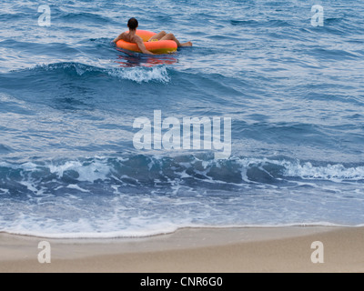 L'uomo fluttuante nel tubo interno in ocean Foto Stock